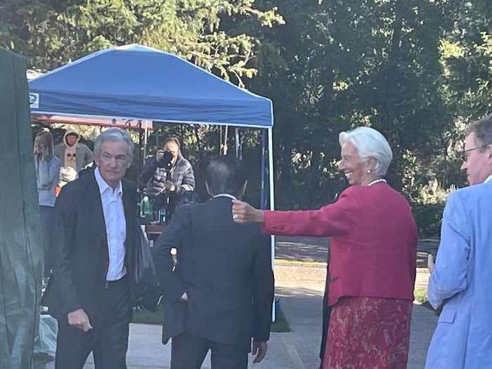 Fed Chair Jerome Powell, left, and ECB President Christine Lagarde greet tourists at the Jackson Lake Lodge in Wyoming, while Bank of Japan Governor Kazuo Ueda, center, continues towards the hotel.